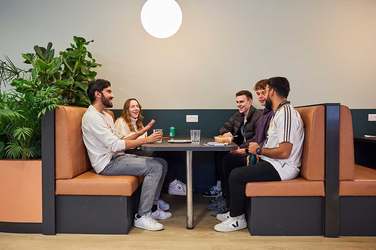 Five graduates sat around a table, chatting Five graduates sat around a table, chatting